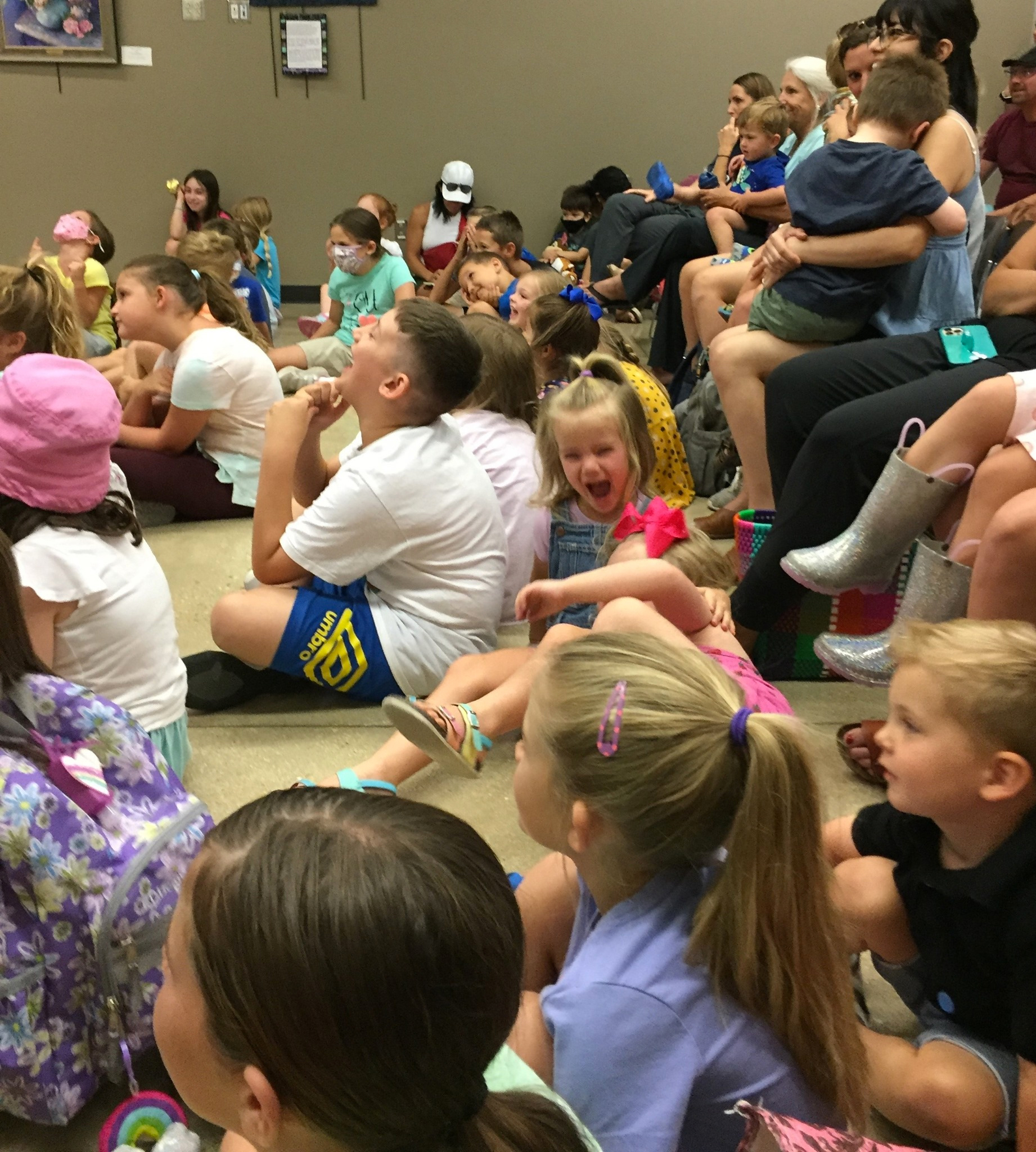 a family audience enjoying a magic and puppet show by The Astonishing Mr. Pitts